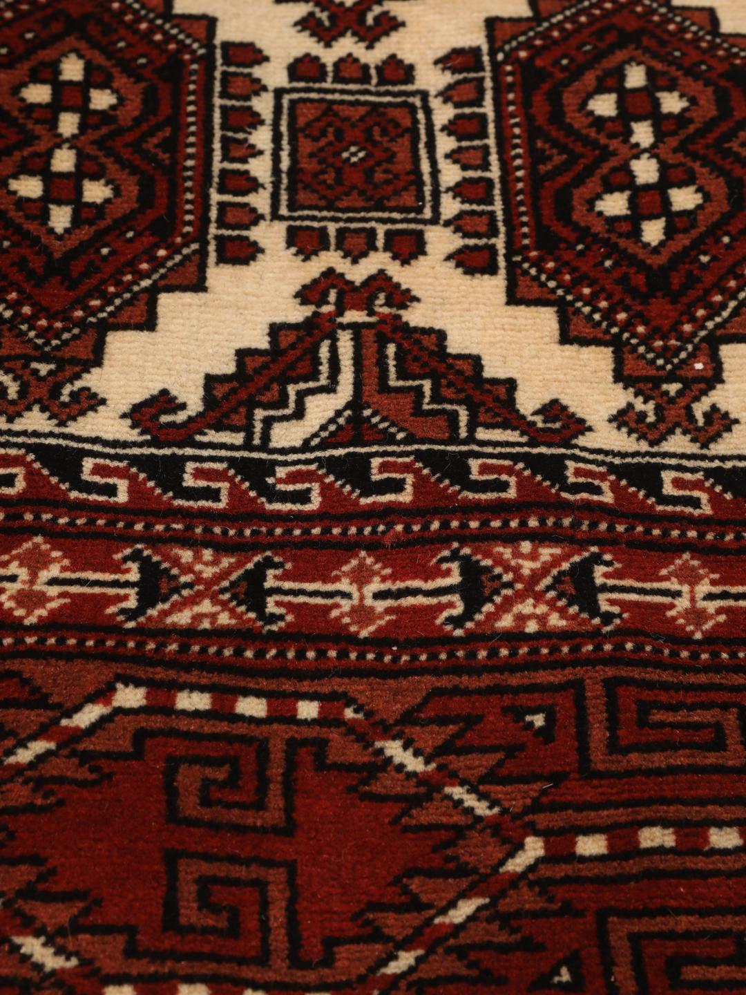 A hand-knotted, one-of-a-kind Turkaman rug with a red field and traditional geometric motifs.