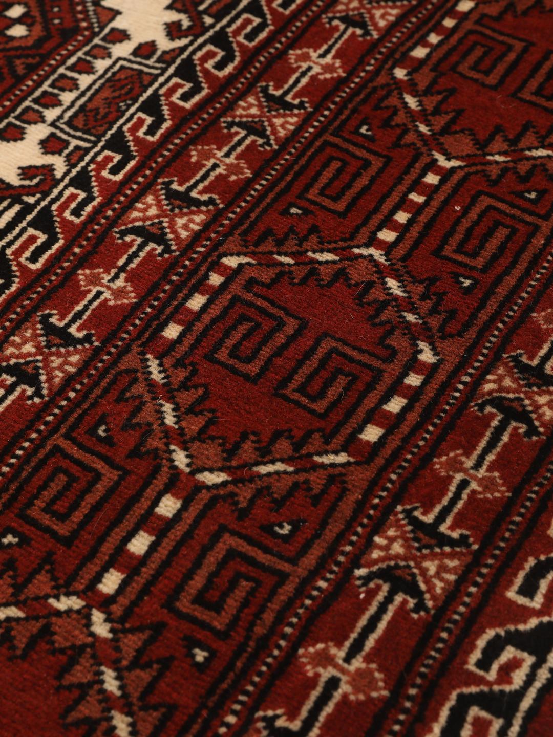 A hand-knotted, one-of-a-kind Turkaman rug with a red field and traditional geometric motifs.