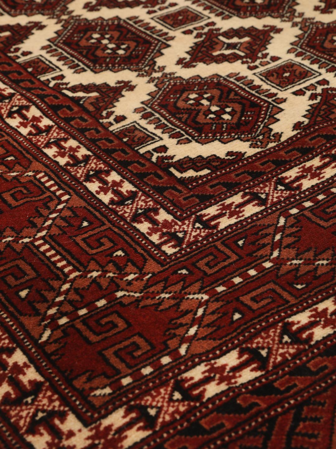 Hand-knotted Turkaman rug from the Middle East in deep red and cream tones.