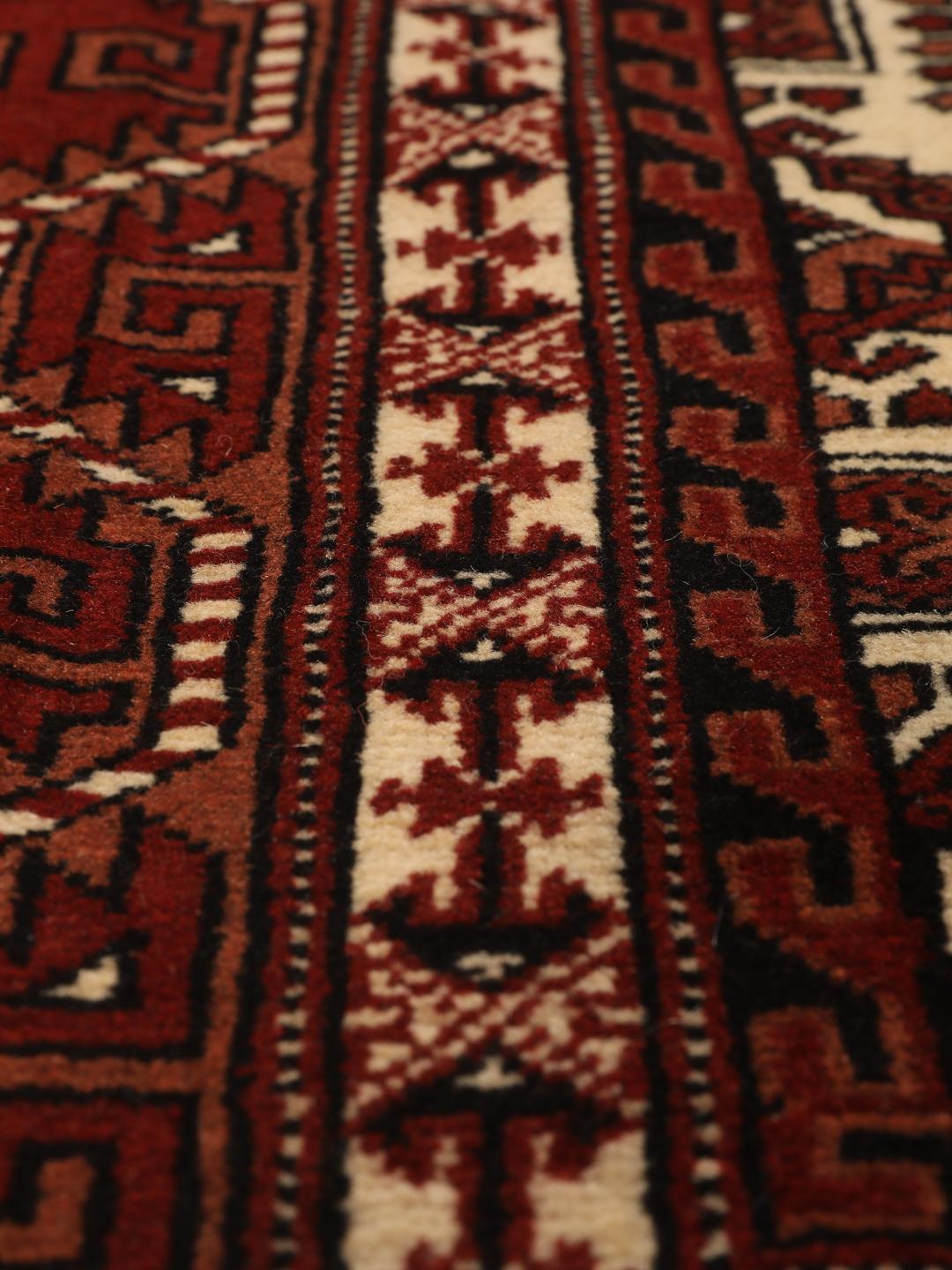 Hand-knotted Turkaman rug from the Middle East in deep red and cream tones.