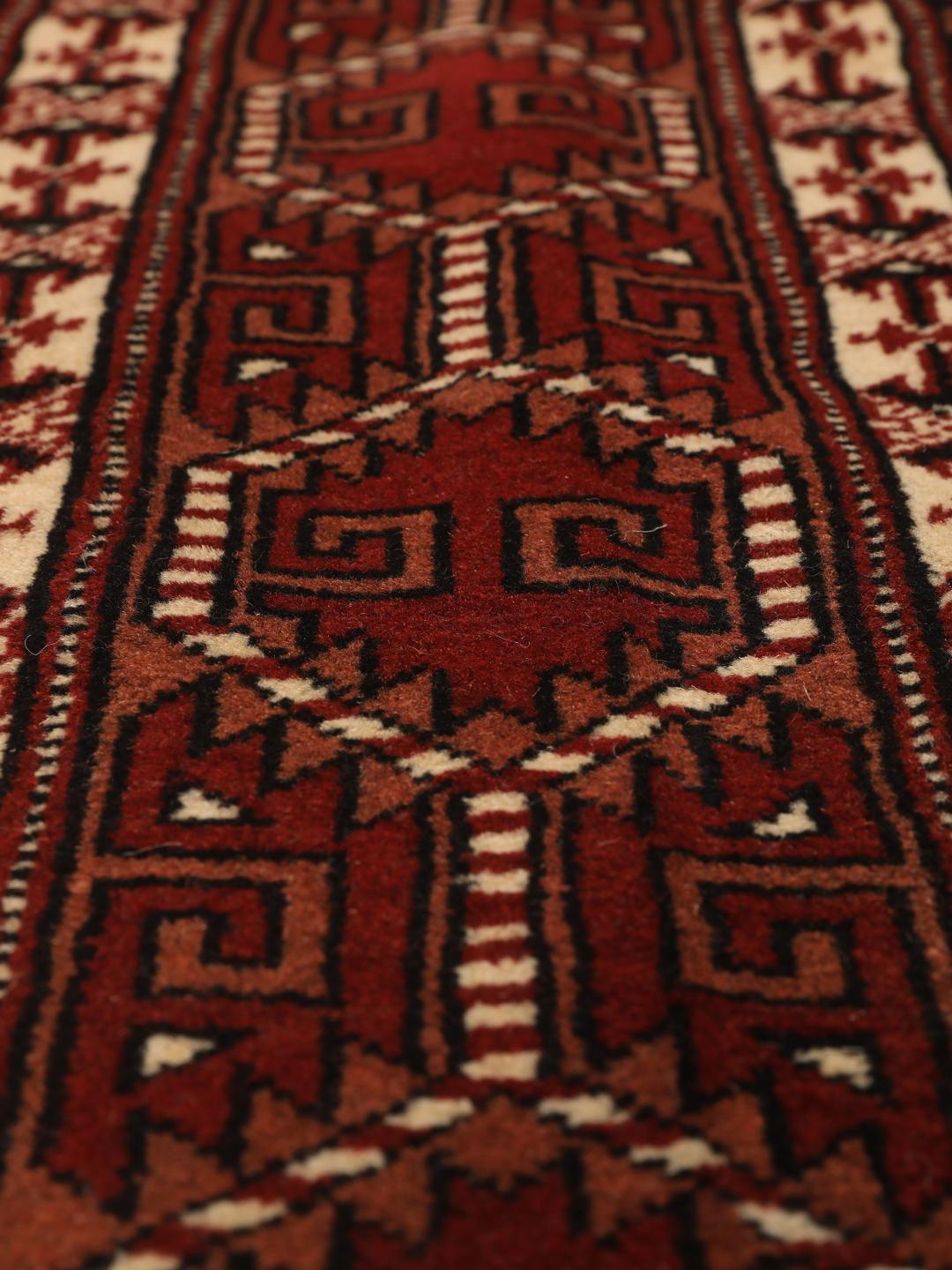 Hand-knotted Turkaman rug from the Middle East in deep red and cream tones.
