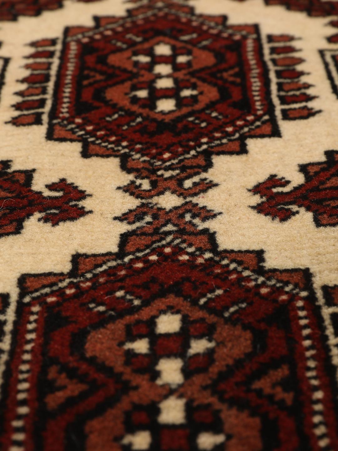 Hand-knotted Turkaman rug from the Middle East in deep red and cream tones.