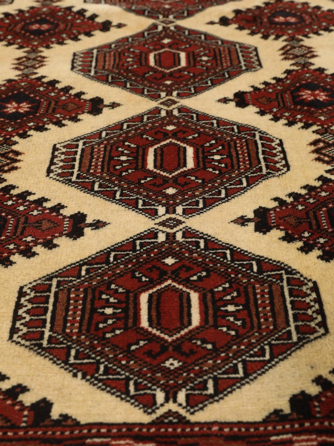 Hand-knotted Turkaman rug from the Middle East in deep red and beige tones.
