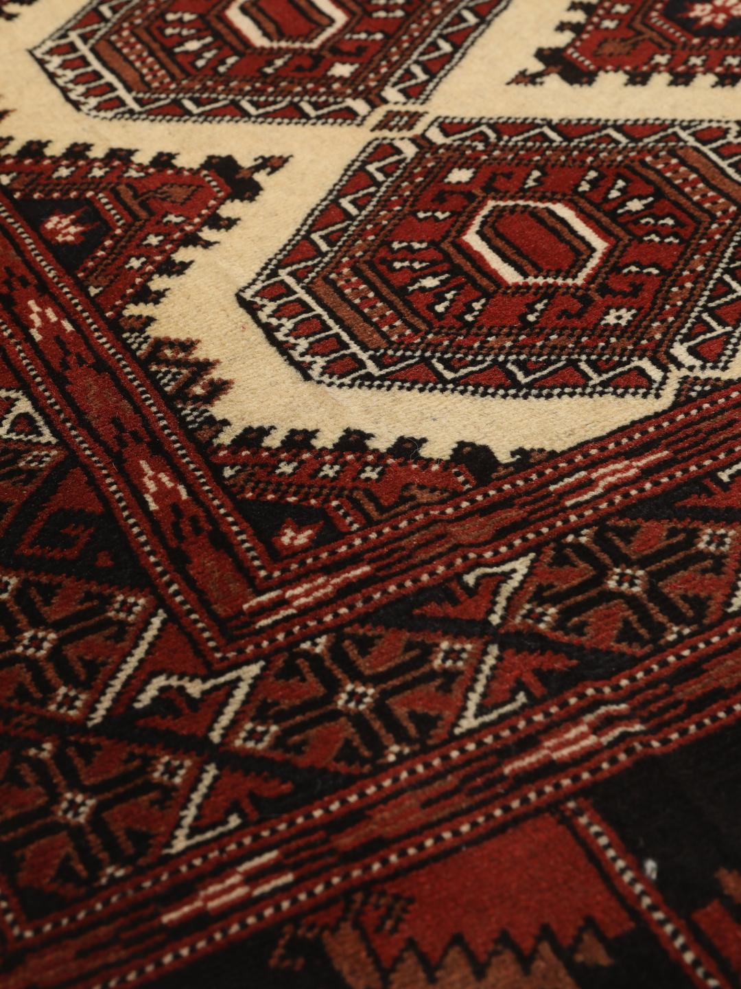 Hand-knotted Turkaman rug from the Middle East in deep red and beige tones.