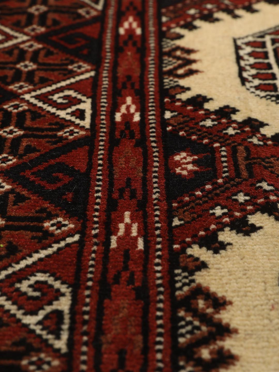 Hand-knotted Turkaman rug from the Middle East in deep red and beige tones.