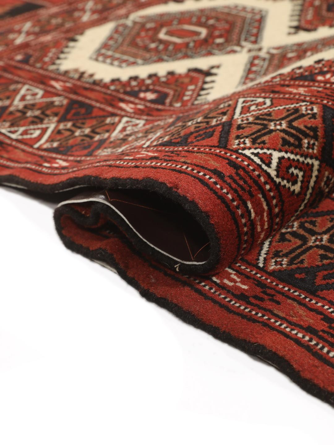 Hand-knotted Turkaman rug from the Middle East in deep red and beige tones.