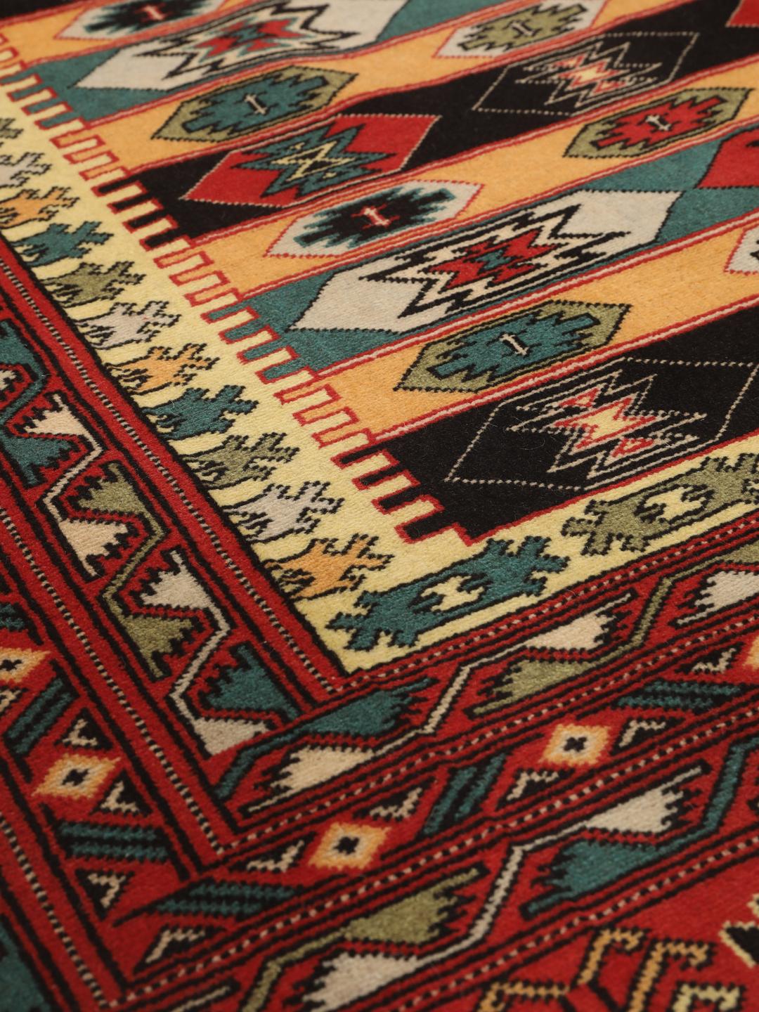 A hand-knotted Turkaman rug from the Middle East with a red base and geometric patterns.