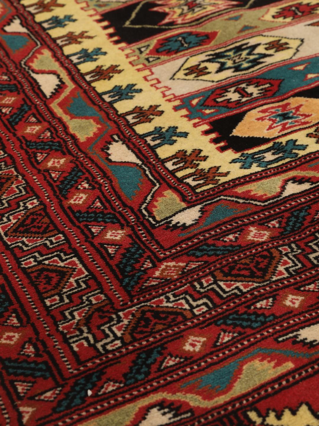 A hand-knotted Turkaman rug from the Middle East with a vibrant red and multicoloured geometric design.