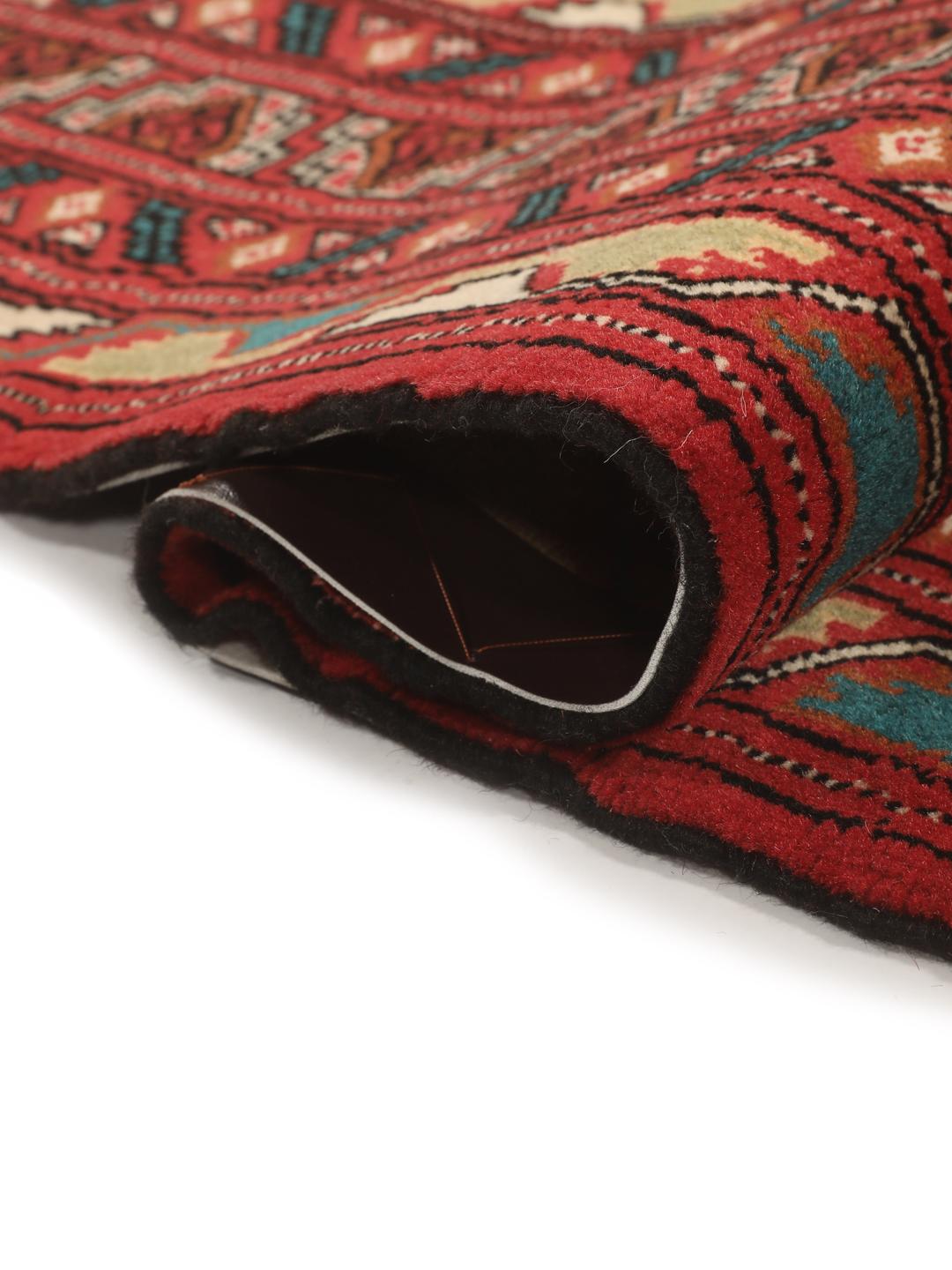 A hand-knotted Turkaman rug from the Middle East with a vibrant red and multicoloured geometric design.