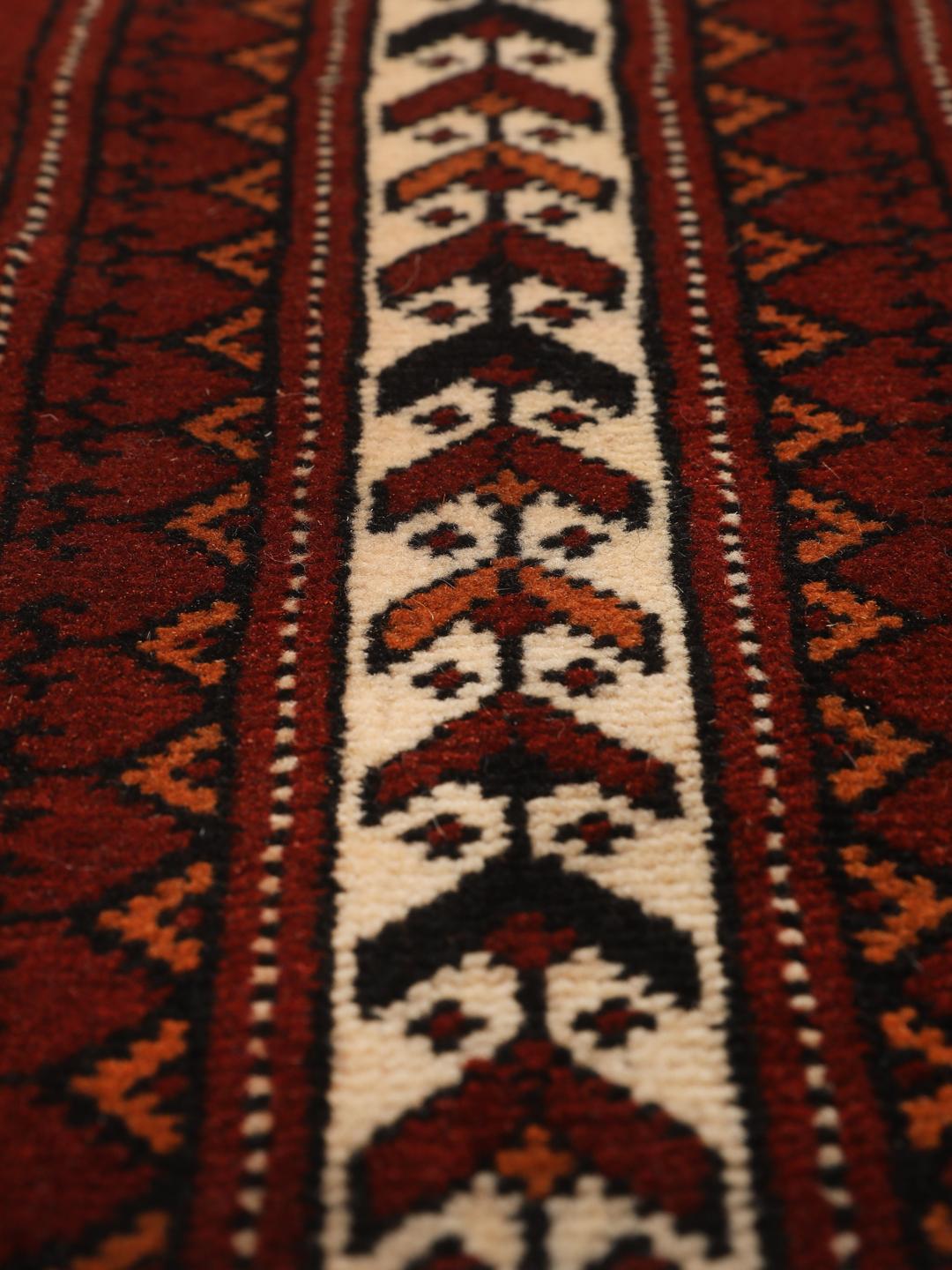 A hand-knotted Turkaman runner from the Middle East featuring a dark-red field with geometric motifs.
