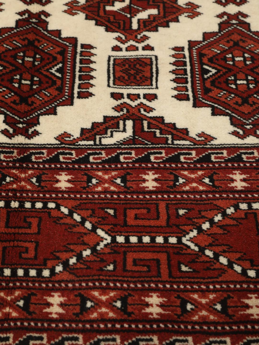 Hand-knotted Turkaman rug from the Middle East with a red and cream geometric design