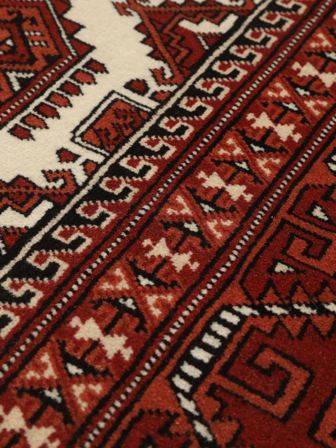Hand-knotted Turkaman rug from the Middle East with a red and cream geometric design