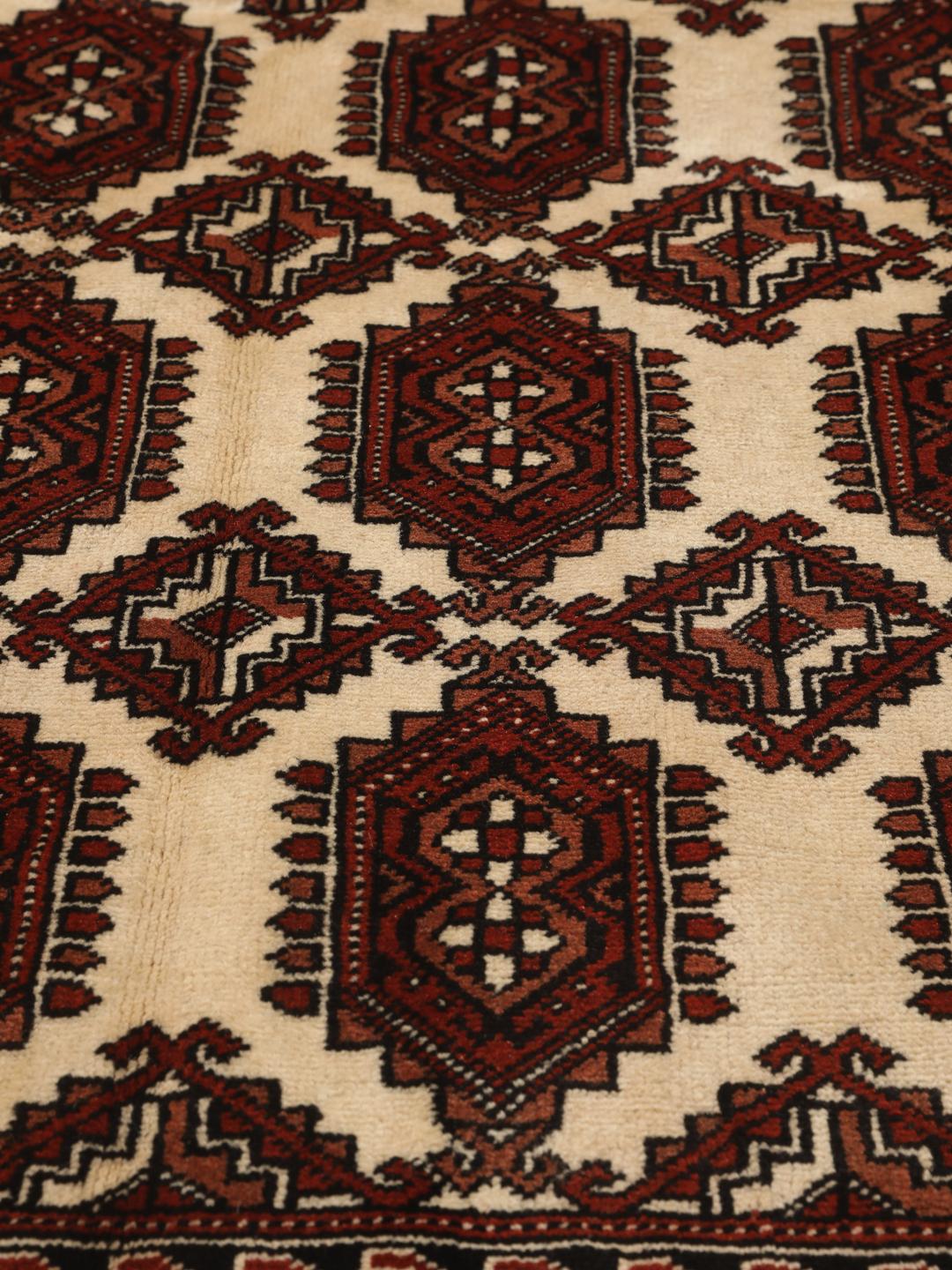 A hand-knotted Turkaman rug with a deep red field and traditional geometric motifs from the Middle East.