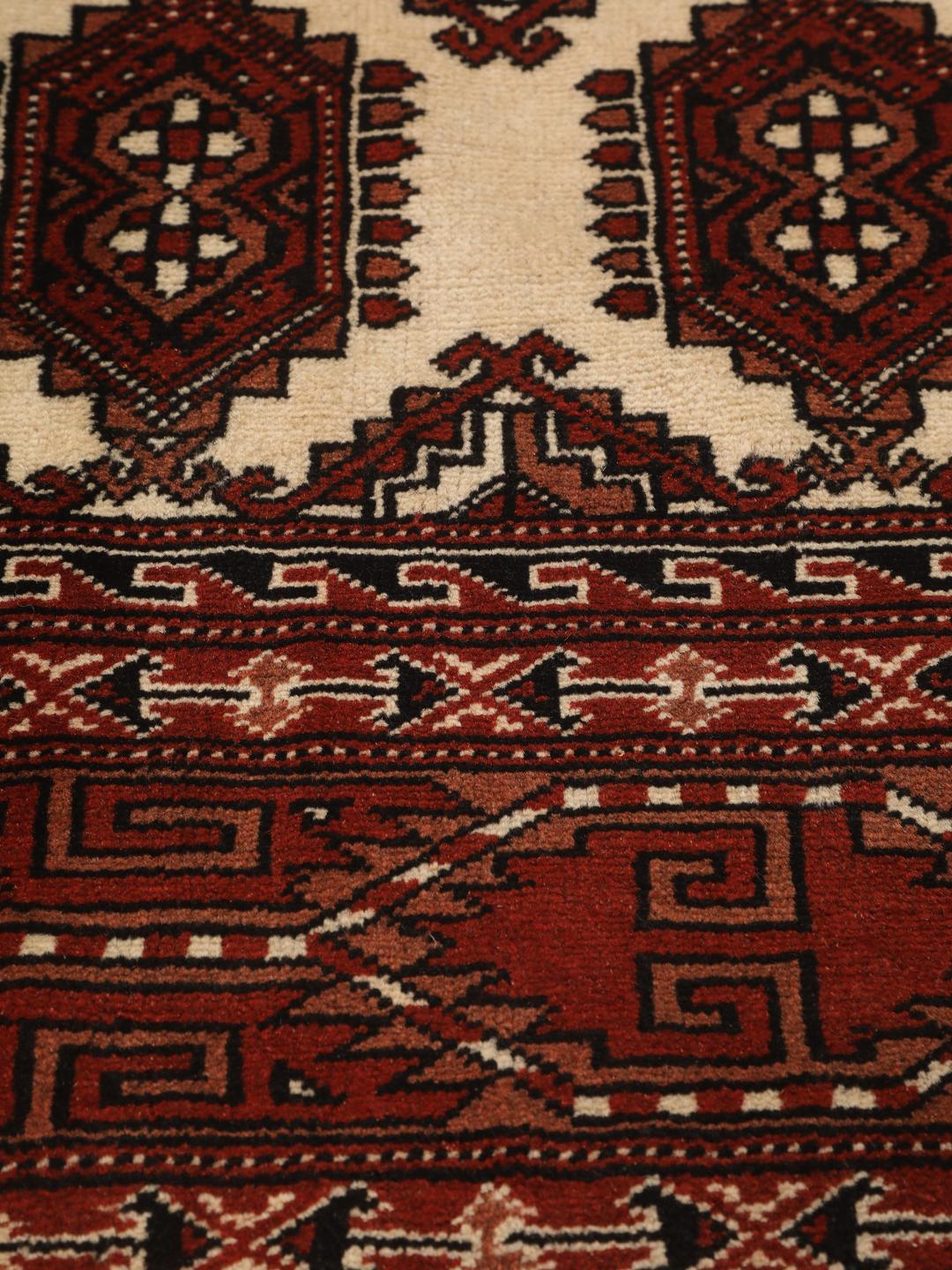 A hand-knotted Turkaman rug with a deep red field and traditional geometric motifs from the Middle East.