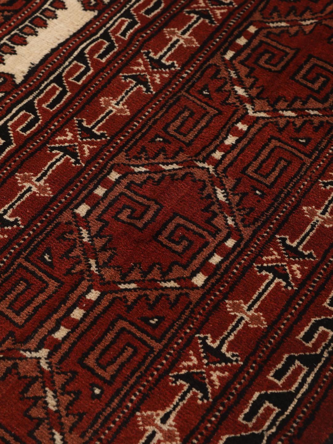 A hand-knotted Turkaman rug with a deep red field and traditional geometric motifs from the Middle East.