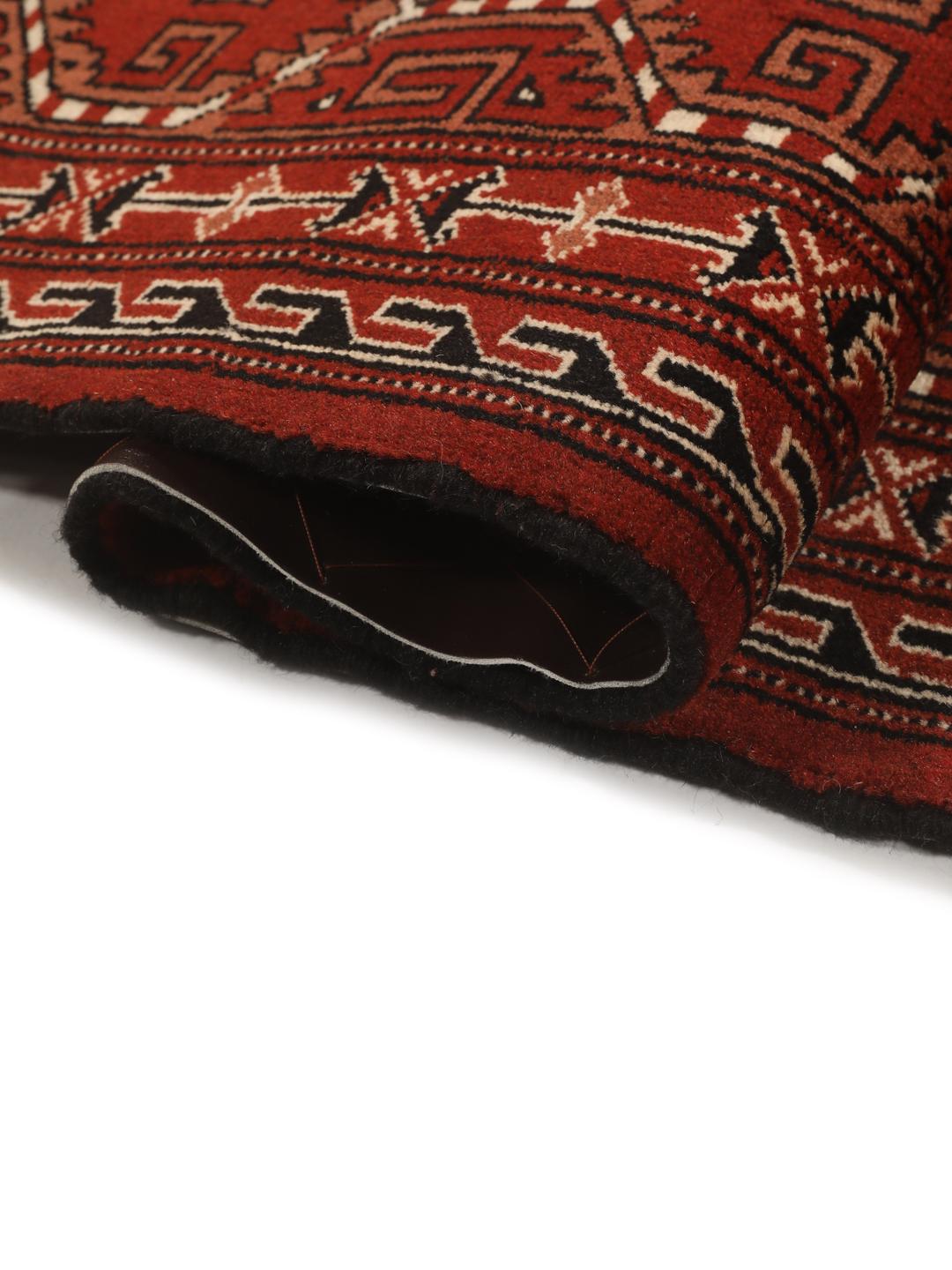 A hand-knotted Turkaman rug with a deep red field and traditional geometric motifs from the Middle East.