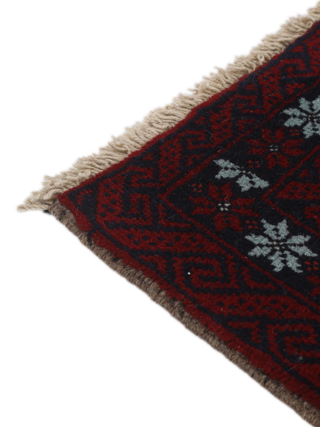 Hand-knotted Baluch rug with geometric motifs in dark-red and black tones.