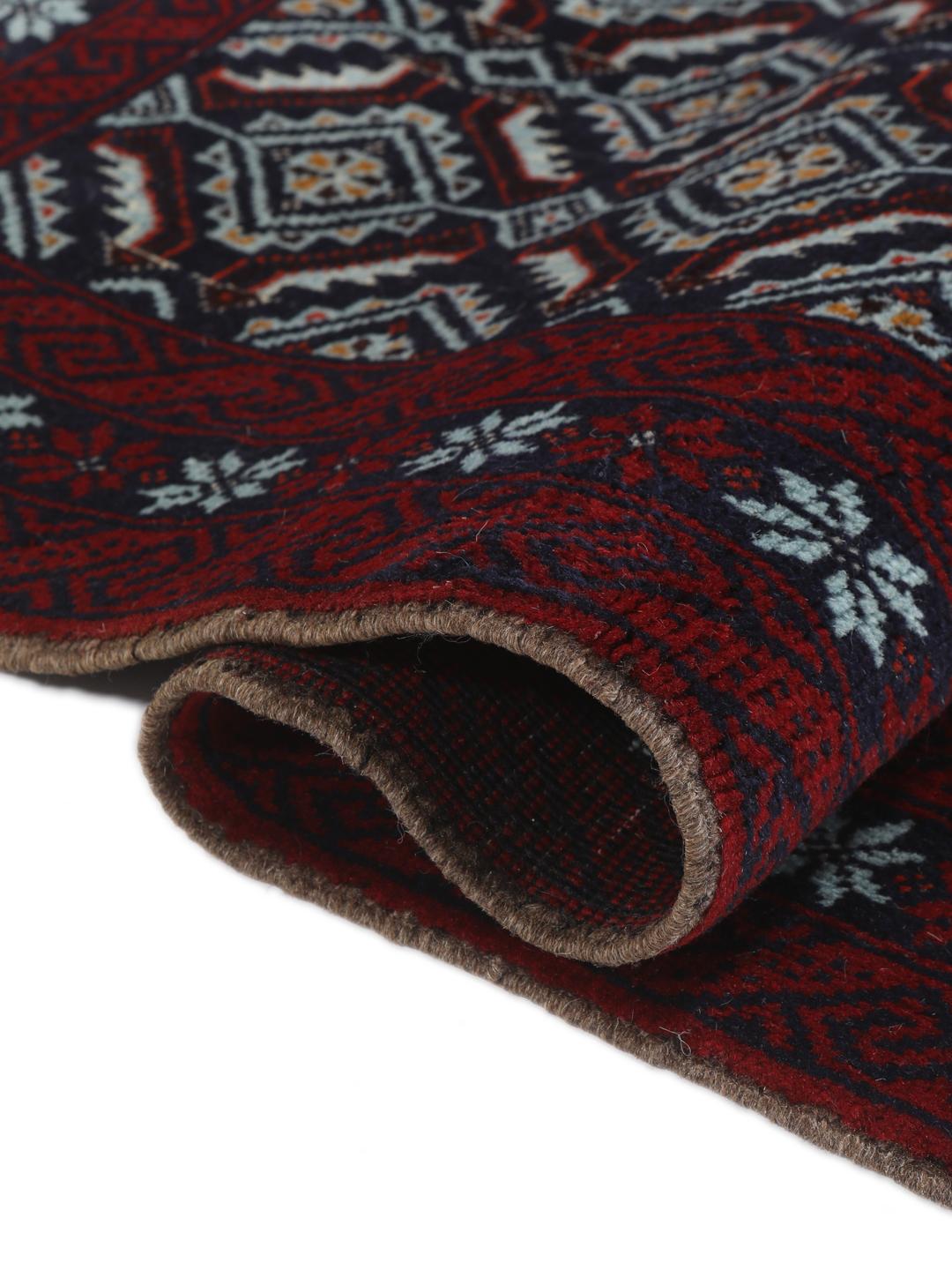 Hand-knotted Baluch rug with geometric motifs in dark-red and black tones.