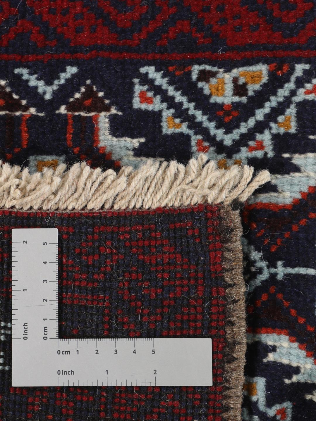 Hand-knotted Baluch rug with geometric motifs in dark-red and black tones.