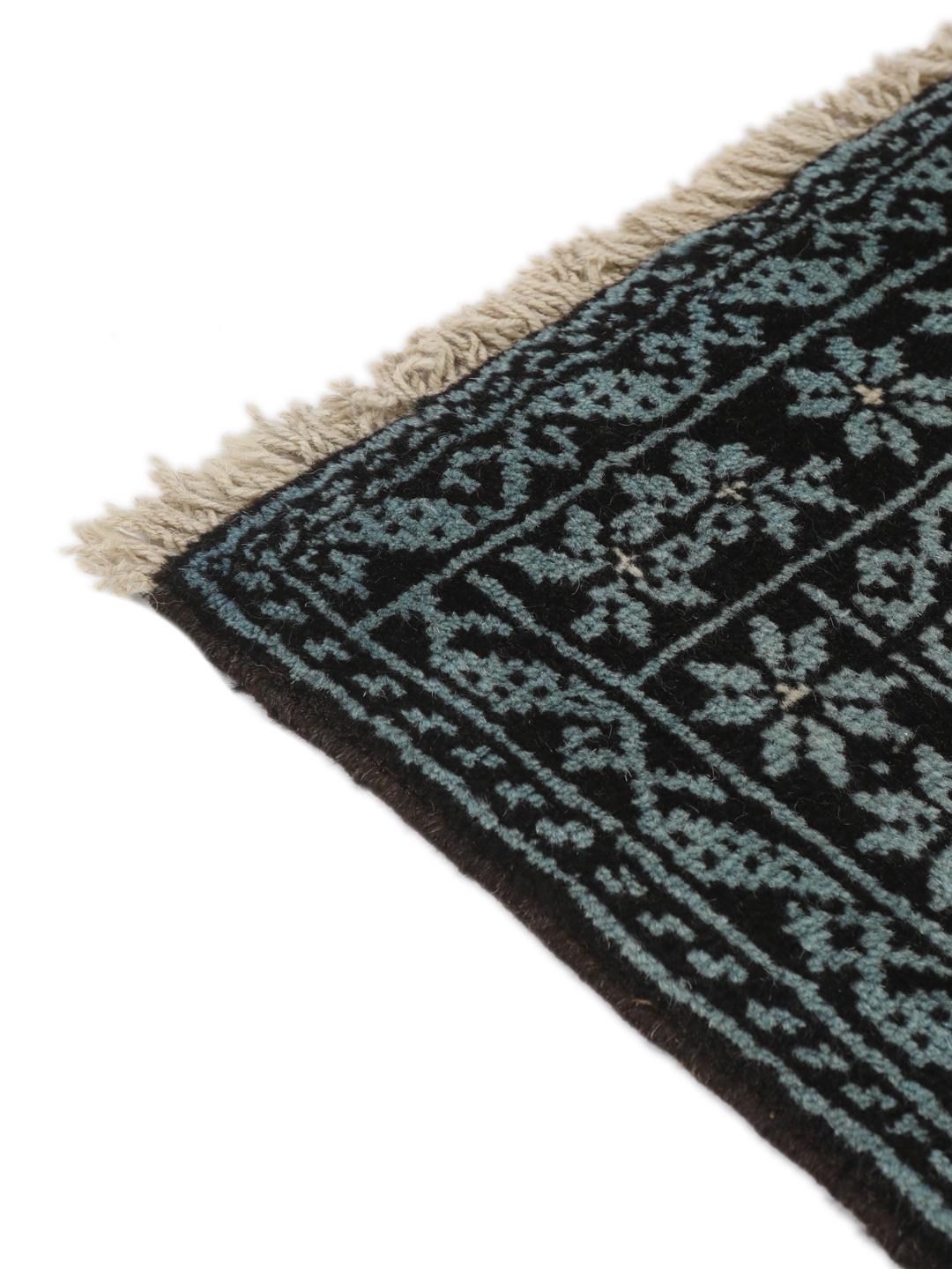 Håndknyttet Baluch-tæppe fra Mellemøsten med et sort og lyseblåt geometrisk design.