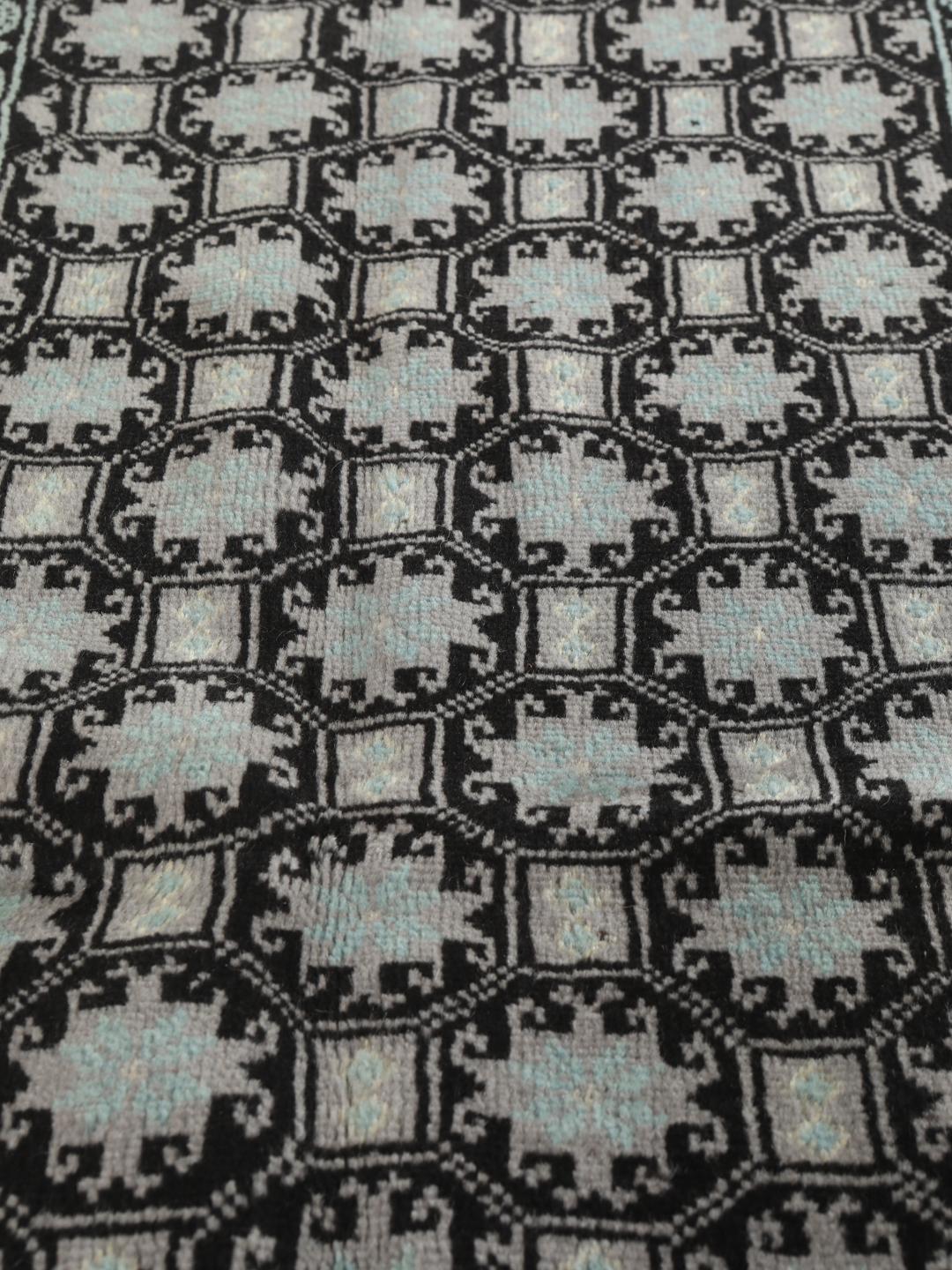 Håndknyttet Baluch-tæppe fra Mellemøsten med et sort og lyseblåt geometrisk design.