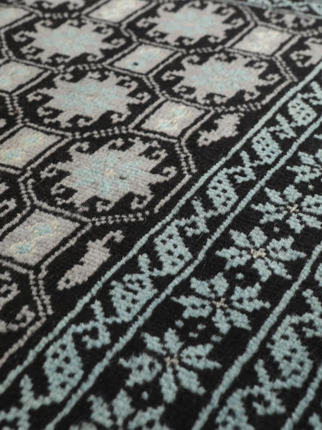 Håndknyttet Baluch-tæppe fra Mellemøsten med et sort og lyseblåt geometrisk design.