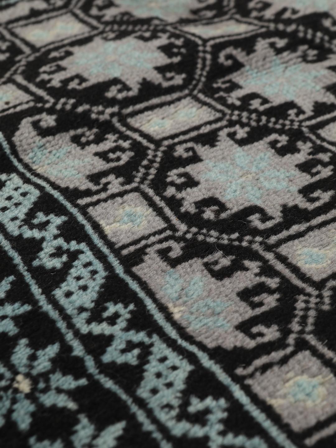 Håndknyttet Baluch-tæppe fra Mellemøsten med et sort og lyseblåt geometrisk design.