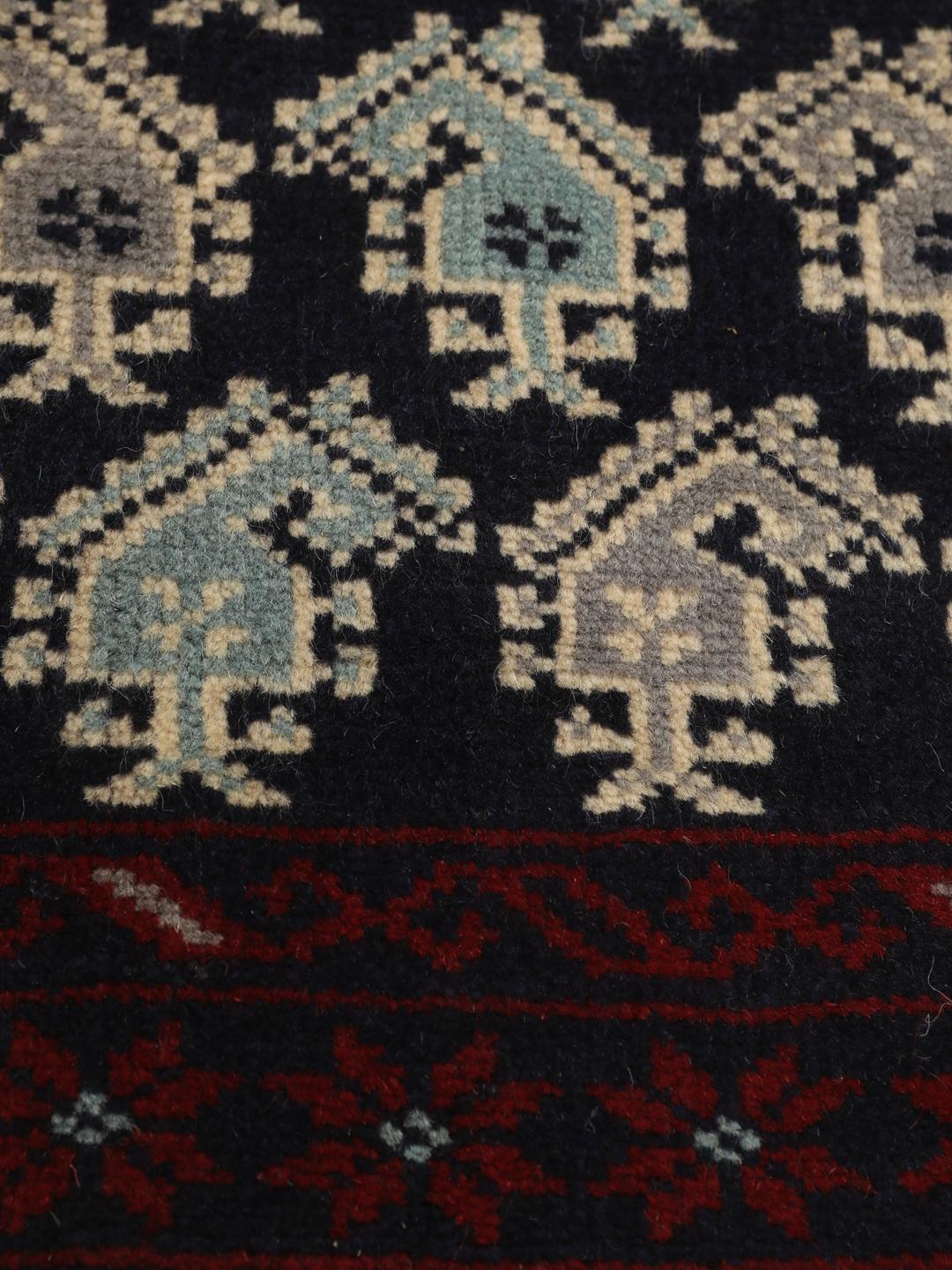 Handgeknoopt Baluch-tapijt met ingewikkelde geometrische motieven in donkerblauw en rood.