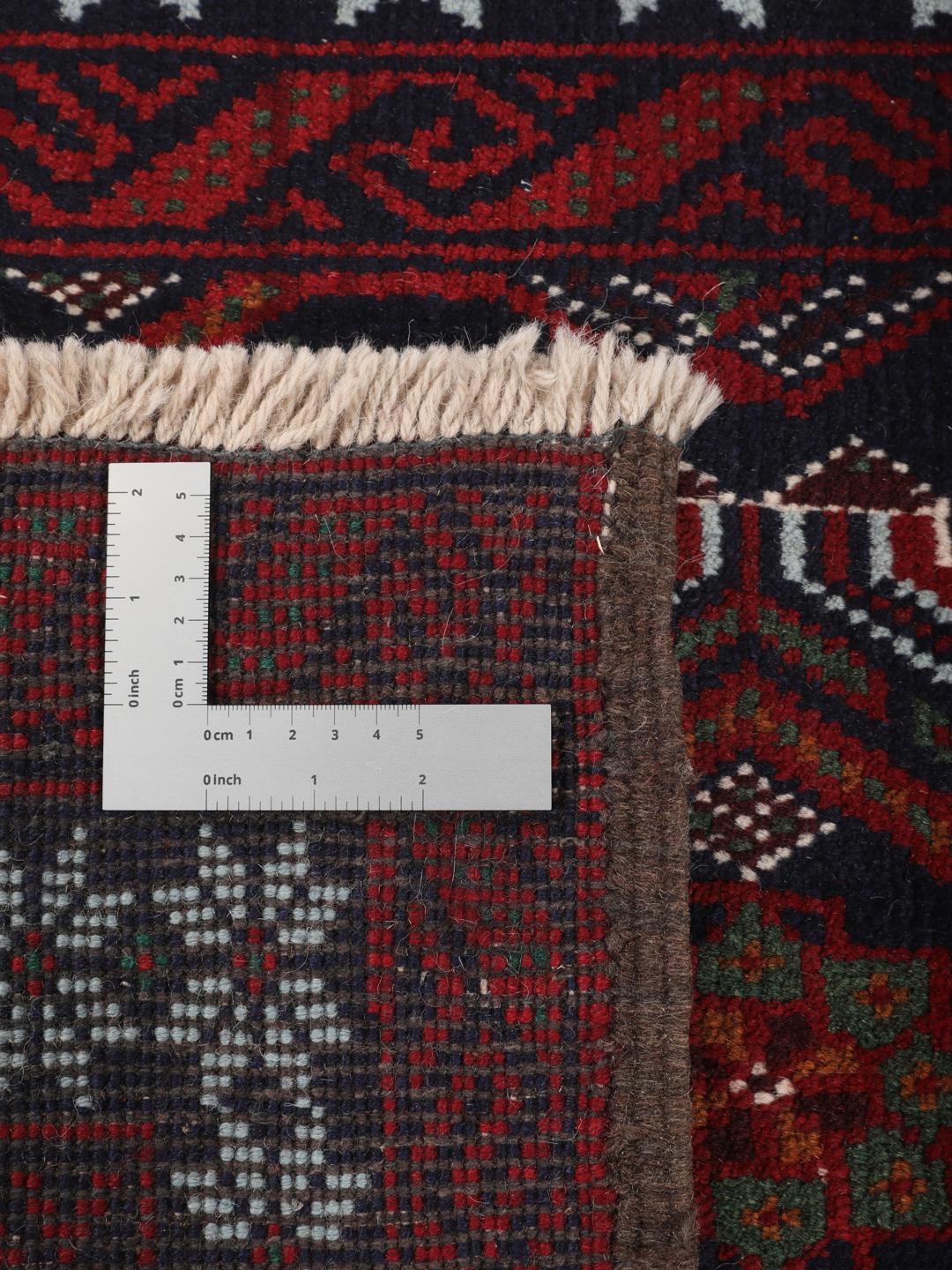 A hand-knotted Baluch rug from the Middle East featuring a dark-red and black geometric pattern.