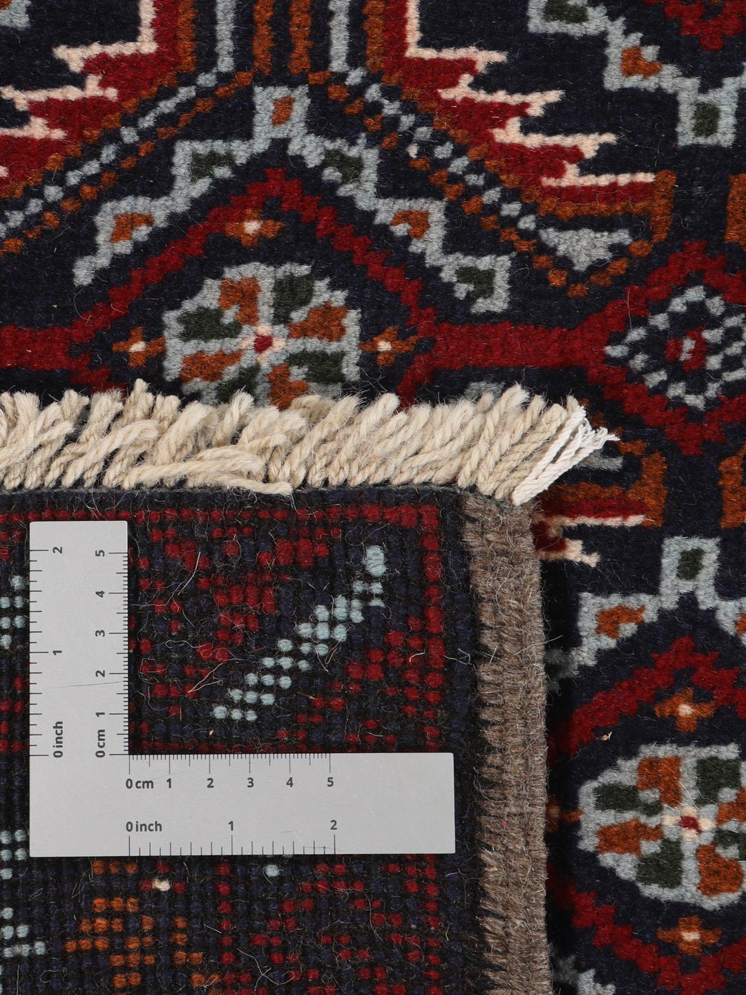 Håndknyttet Baluch-tæppe fra Mellemøsten med et mørkerødt og marineblåt mønster.