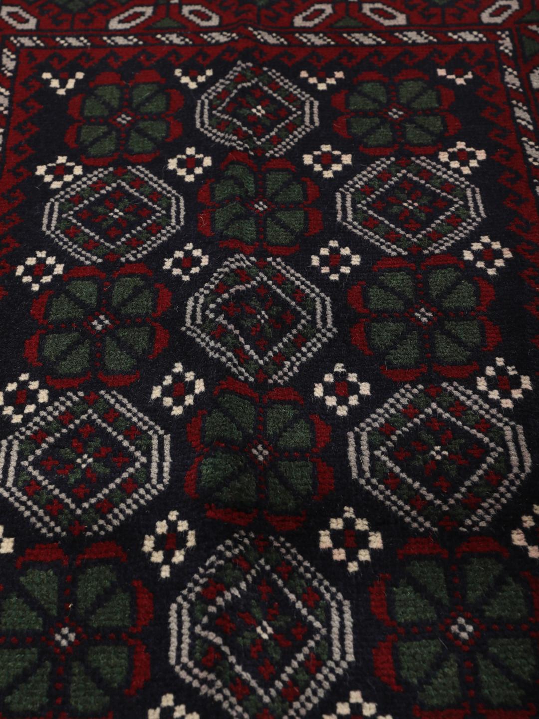Handmade Baluch rug from the Middle East in dark blue and red tones.