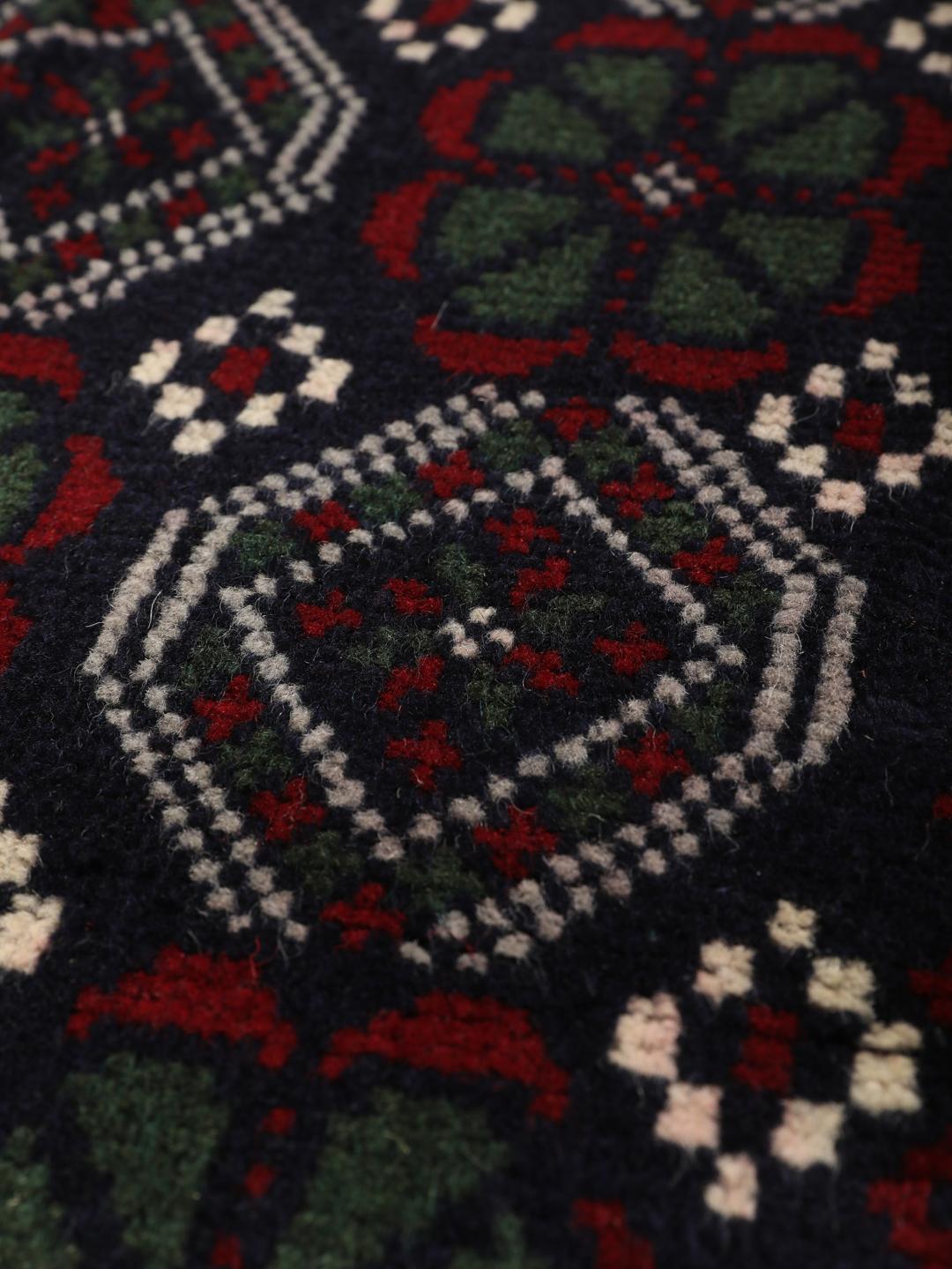 Handmade Baluch rug from the Middle East in dark blue and red tones.