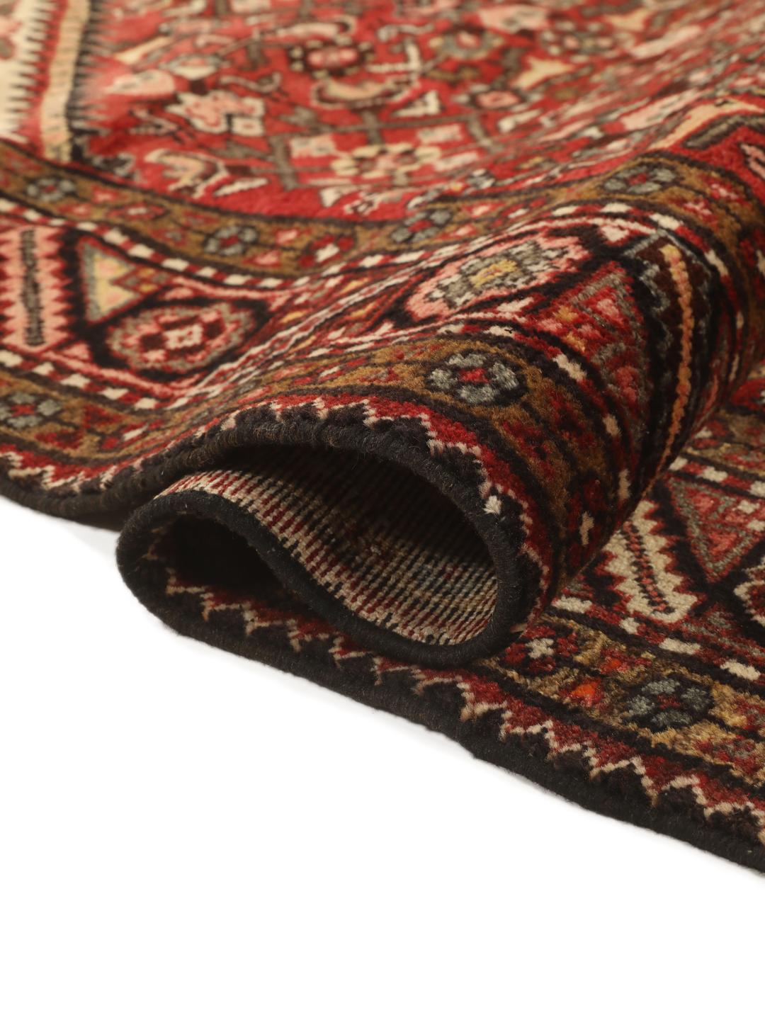Een handgeknoopt donkerrood Hosseinabad-tapijt met ingewikkelde geometrische patronen.