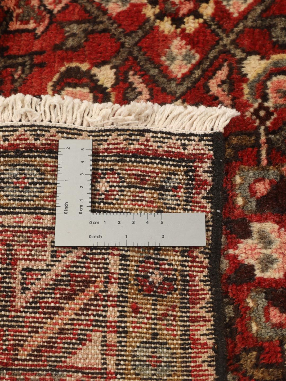 Een handgeknoopt donkerrood Hosseinabad-tapijt met ingewikkelde geometrische patronen.