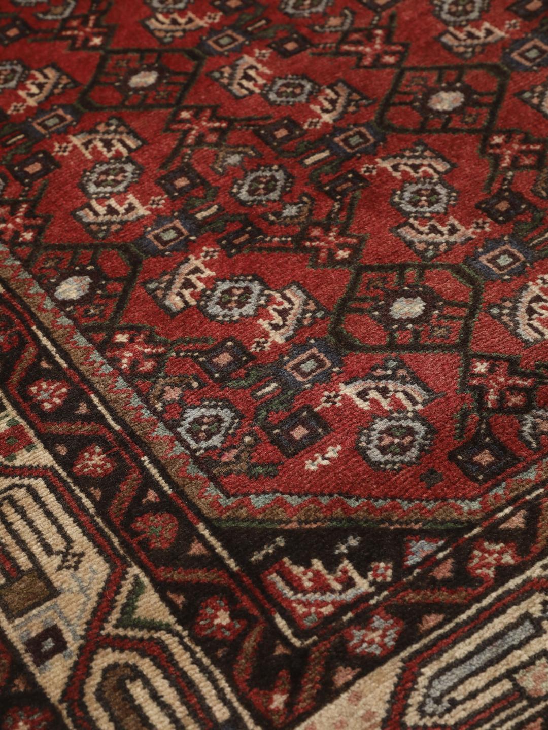 Handgeknoopt Hosseinabad-tapijt uit het Midden-Oosten met een rood veld en geometrische patronen.