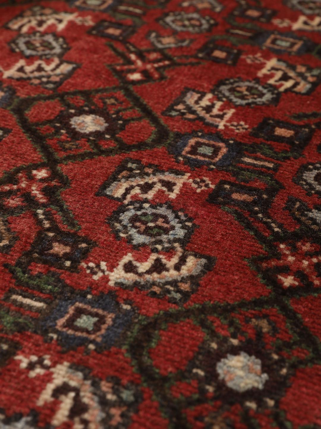 Handgeknoopt Hosseinabad-tapijt uit het Midden-Oosten met een rood veld en geometrische patronen.