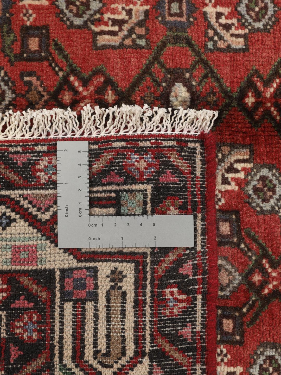 Handgeknoopt Hosseinabad-tapijt uit het Midden-Oosten met een rood veld en geometrische patronen.