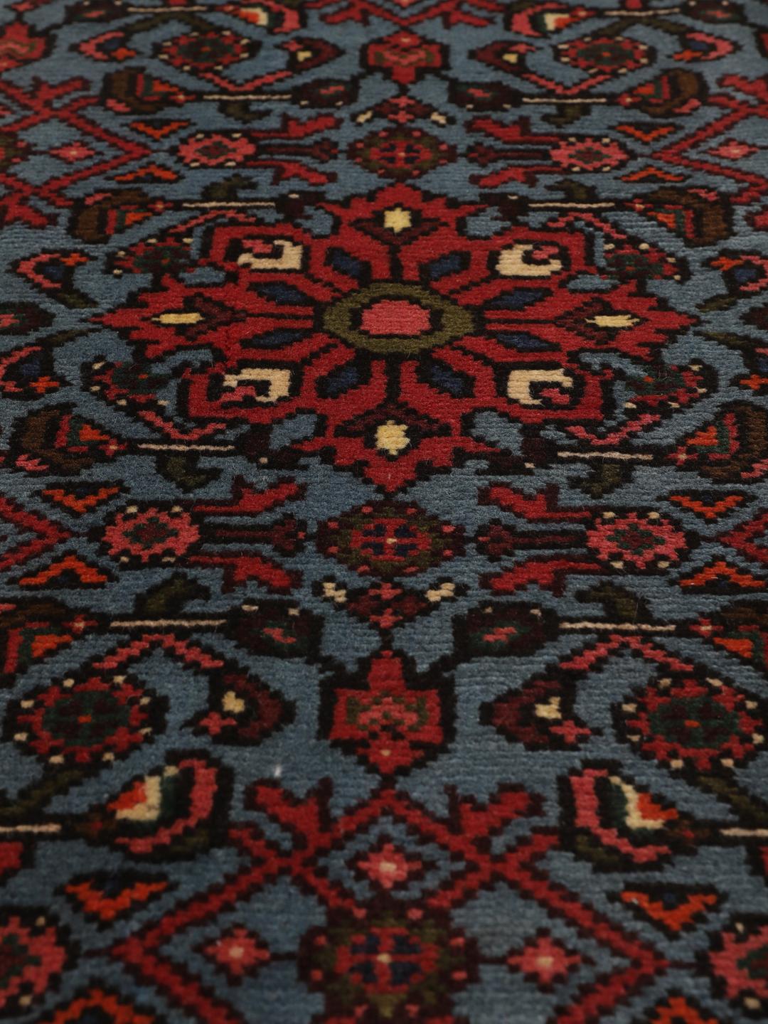 Een klein handgeknoopt Hosseinabad-tapijt uit het Midden-Oosten met een blauw en rood geometrisch patroon