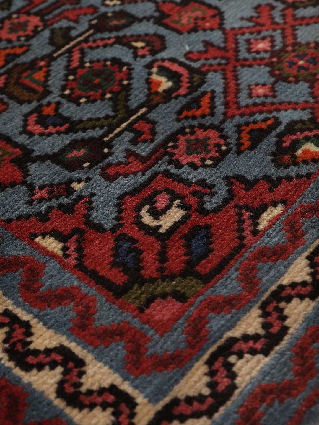 Een klein handgeknoopt Hosseinabad-tapijt uit het Midden-Oosten met een blauw en rood geometrisch patroon