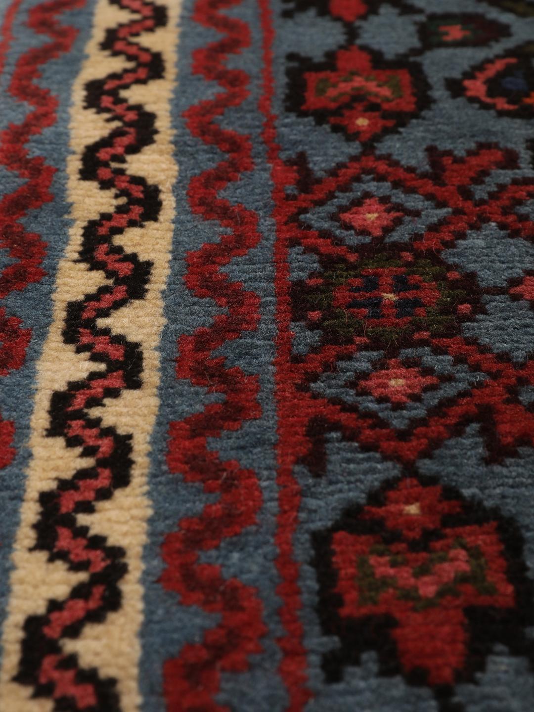 Een klein handgeknoopt Hosseinabad-tapijt uit het Midden-Oosten met een blauw en rood geometrisch patroon