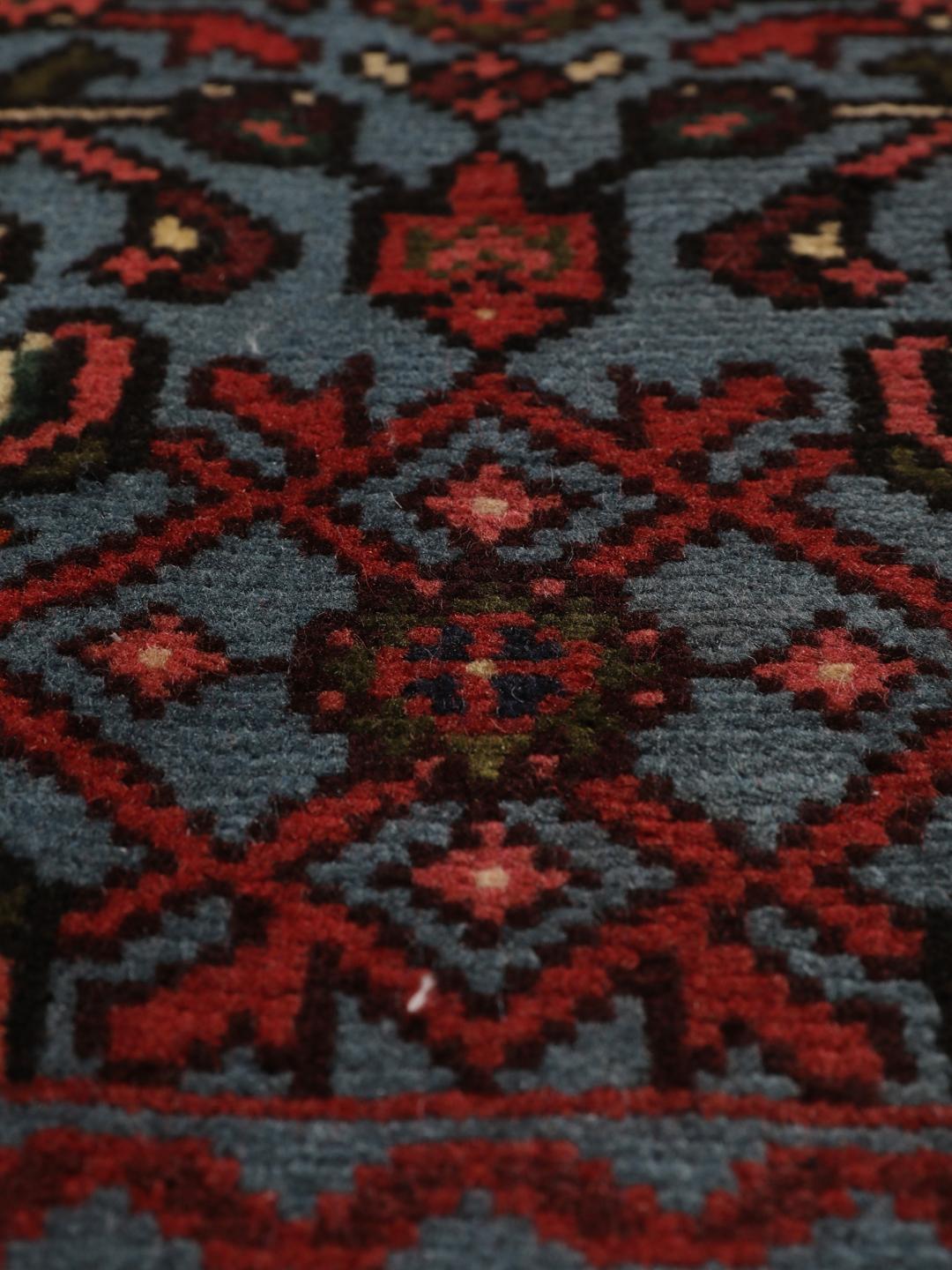 Een klein handgeknoopt Hosseinabad-tapijt uit het Midden-Oosten met een blauw en rood geometrisch patroon