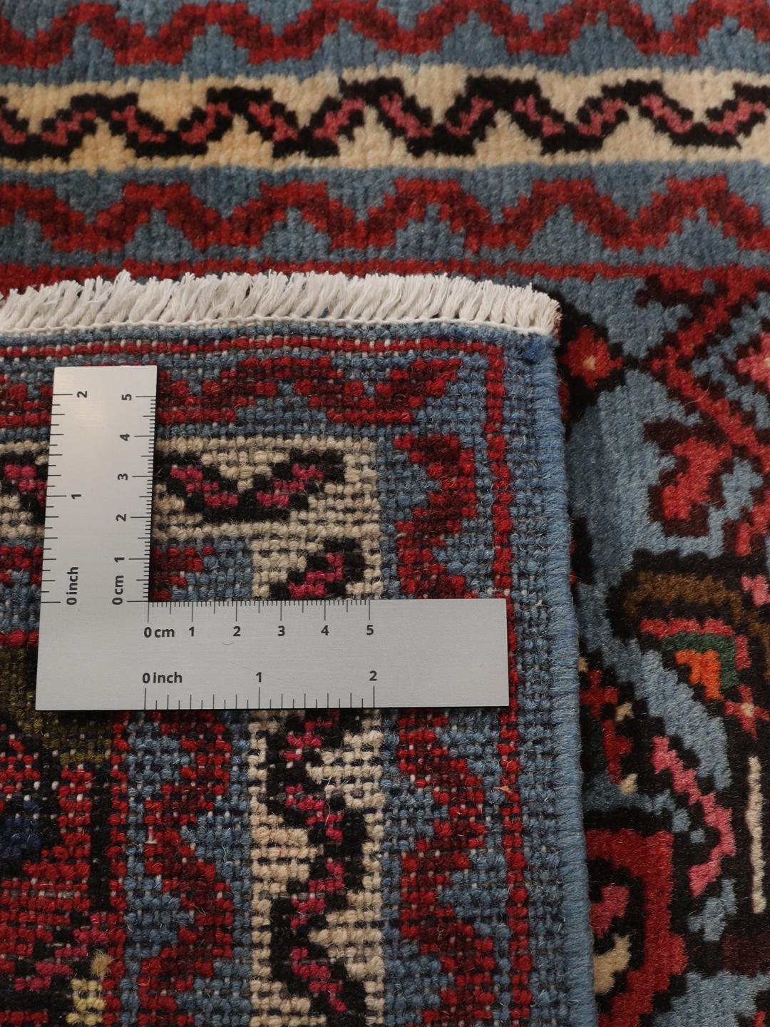 Een klein handgeknoopt Hosseinabad-tapijt uit het Midden-Oosten met een blauw en rood geometrisch patroon