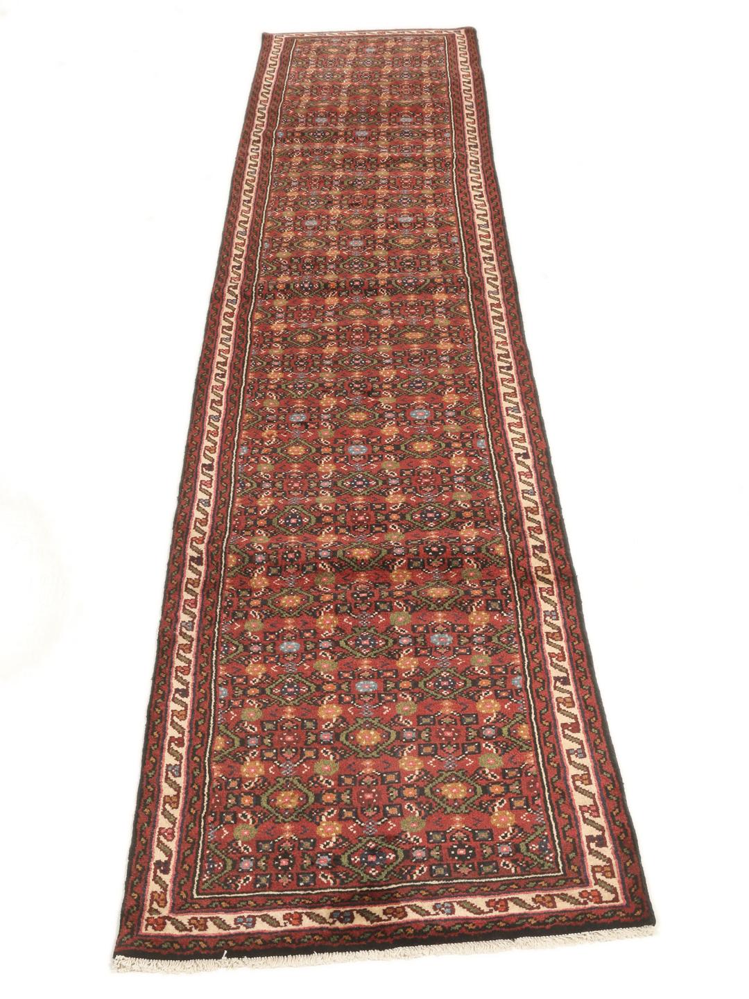 A long, hand-knotted red Hosseinabad runner with a geometric pattern.