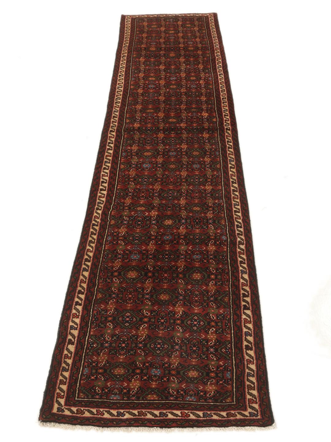 A long, hand-knotted red Hosseinabad runner with a geometric pattern.