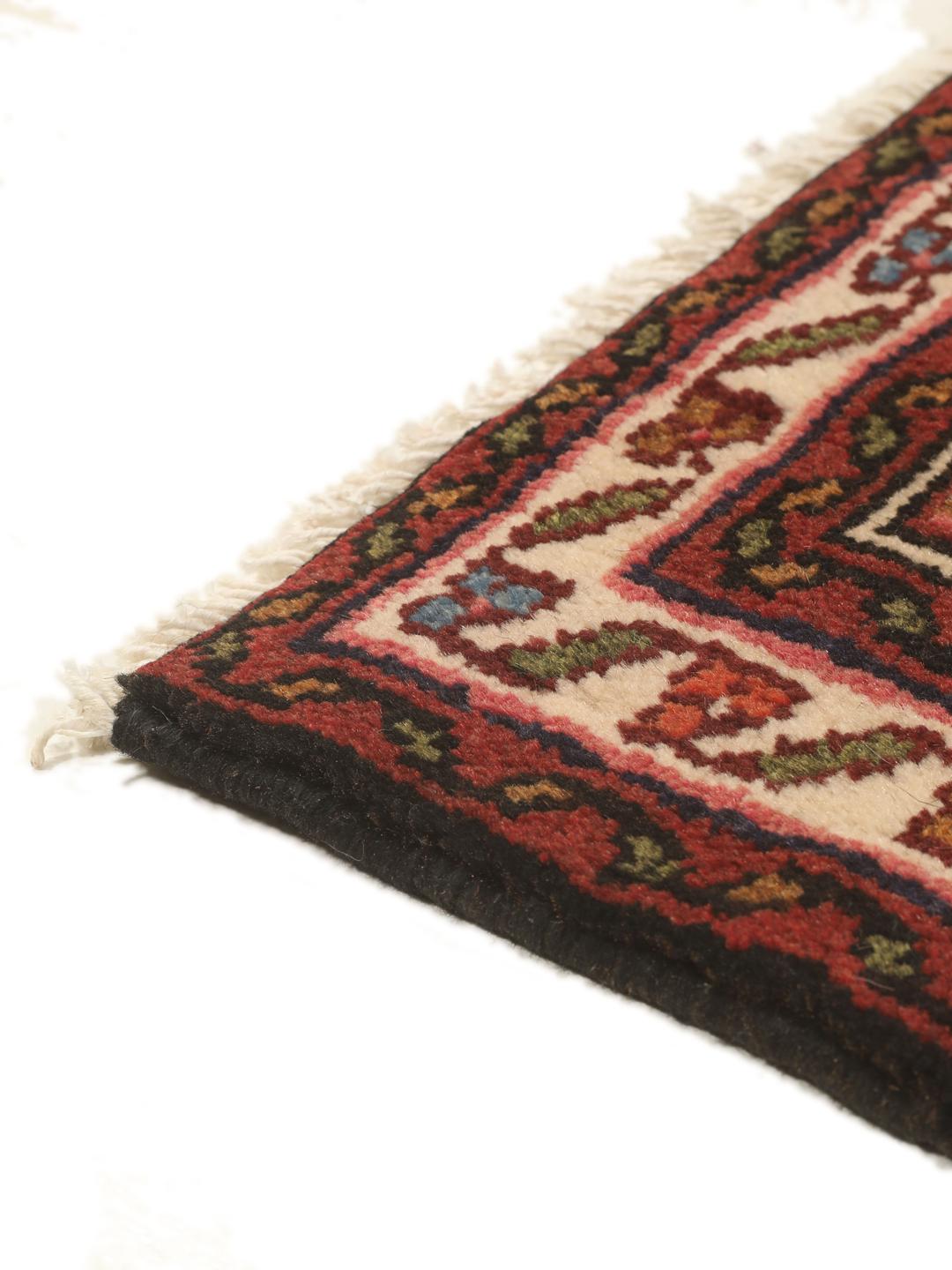 A long, hand-knotted red Hosseinabad runner with a geometric pattern.