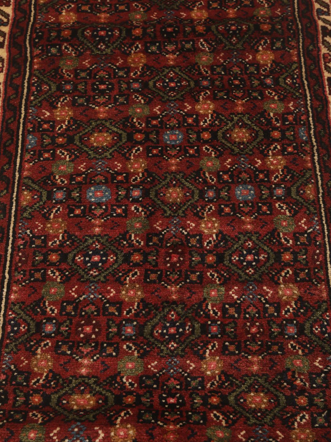 A long, hand-knotted red Hosseinabad runner with a geometric pattern.