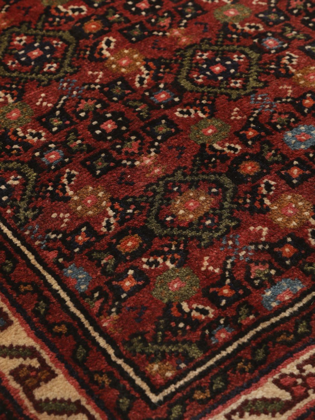 A long, hand-knotted red Hosseinabad runner with a geometric pattern.