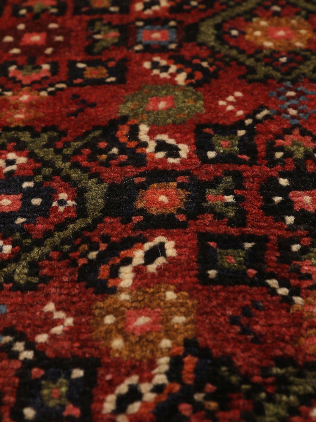 A long, hand-knotted red Hosseinabad runner with a geometric pattern.