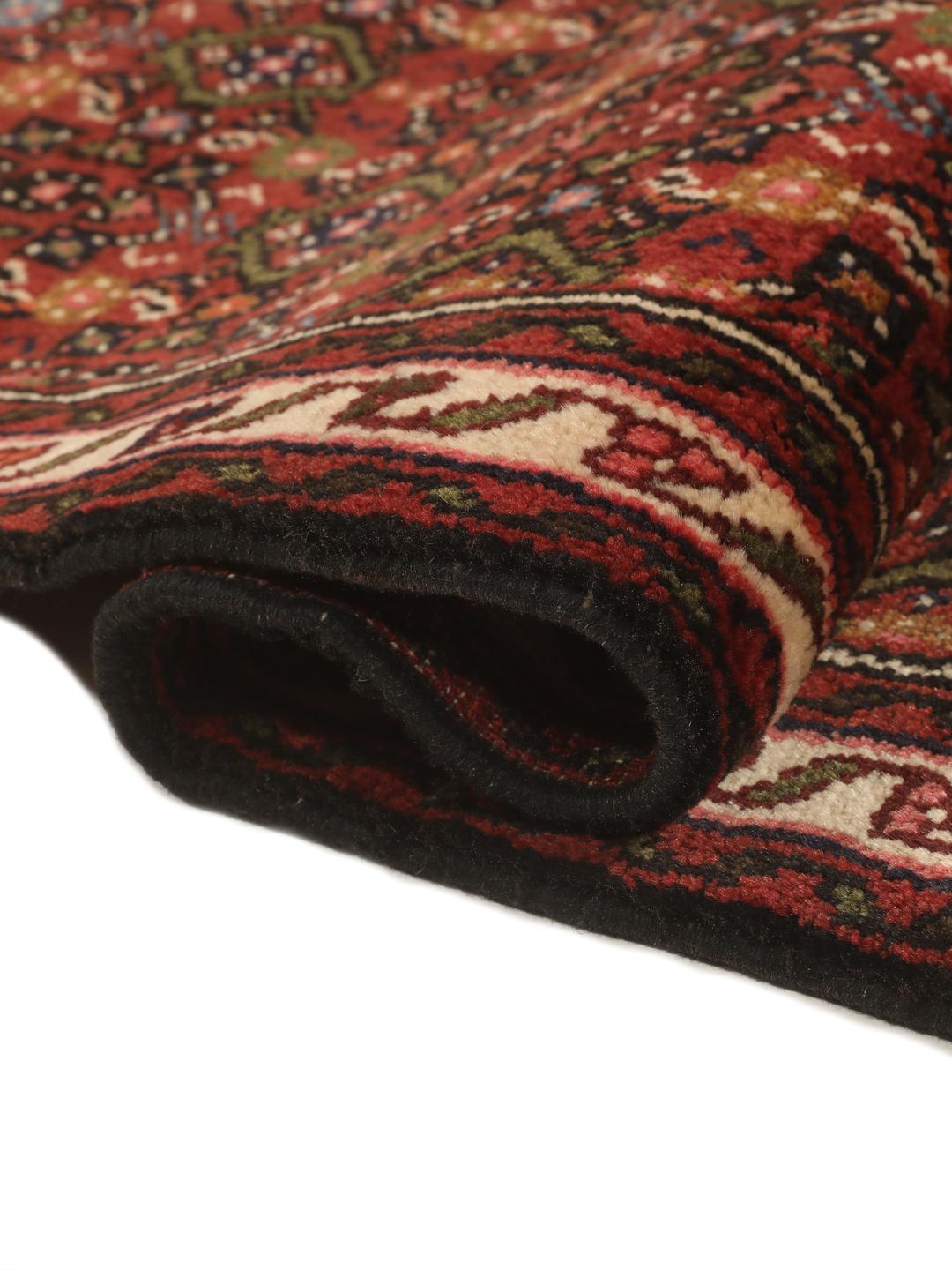 A long, hand-knotted red Hosseinabad runner with a geometric pattern.