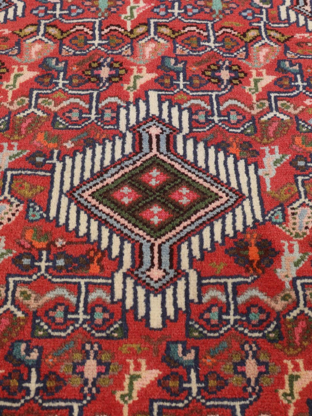 Hand-knotted Asadabad rug from the Middle East with a vibrant red field and geometric patterns